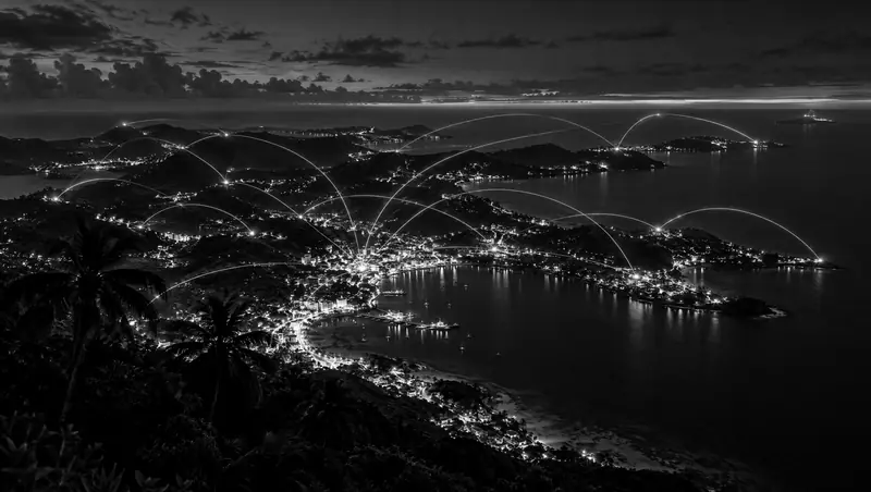 Vista nocturna de una costa caribeña con luces de ciudad conectadas por una red de datos